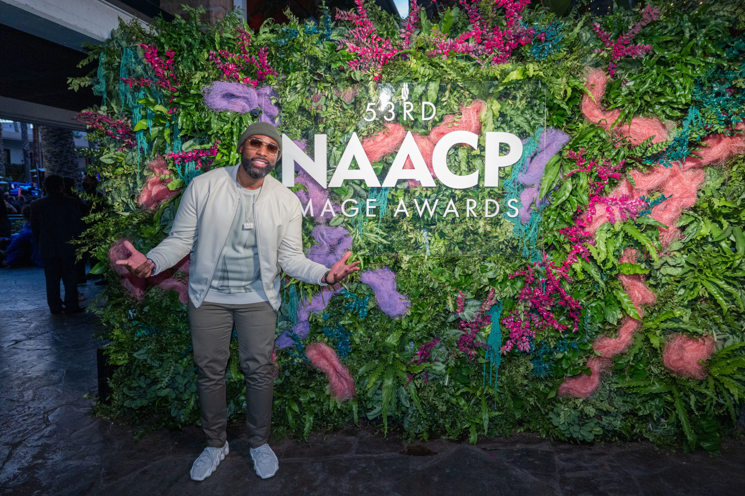 Isaac Yowman standing in front of floral wall that reads "53rd NAACP Image Awards"